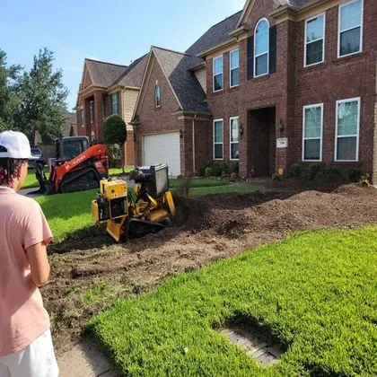Stump grinding with skid steer at brick home